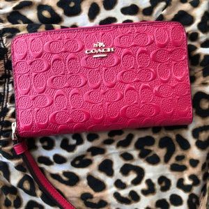 Pink leather coach wallet with tag inside.